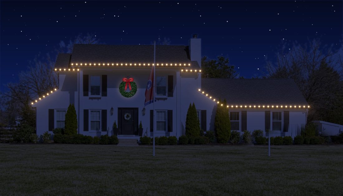 A wide colonial home with C9s and a wreath.